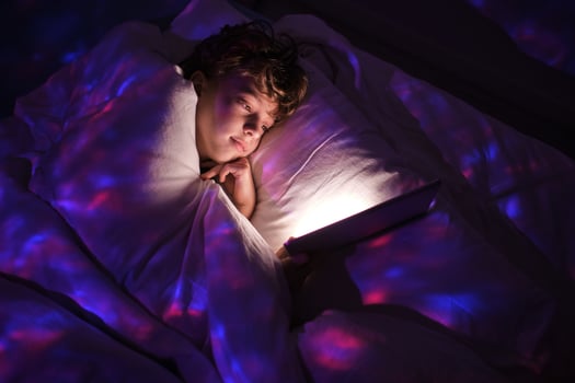 Boy browsing tablet in dark bedroom photo