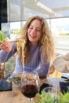 Satisfied fair haired woman eating ramen in restaurant photo