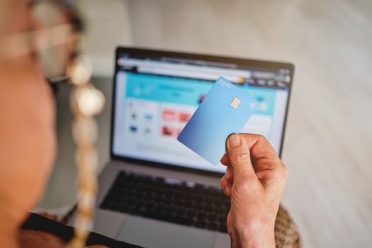 A woman holding a credit card in front of a laptop photo