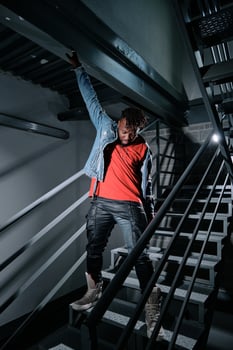 Ethnic guy putting on jeans jacket on staircase photo