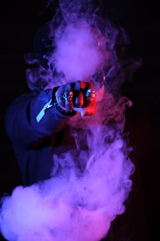 Unrecognizable man surrounded by smoke in neon lighting photo