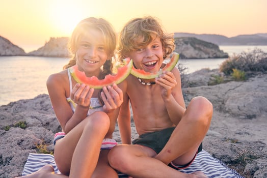 Happy brother and sister with watermelon slices at seaside photo