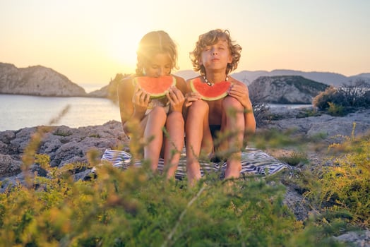Happy siblings eating watermelon on seashore photo