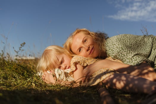 Mother and daughter lying on grassy ground in countryside photo