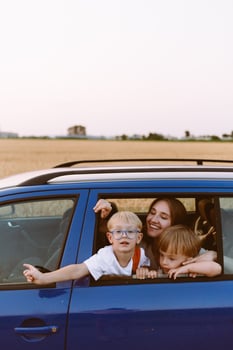 Young woman with little sons sitting in car in countryside photo