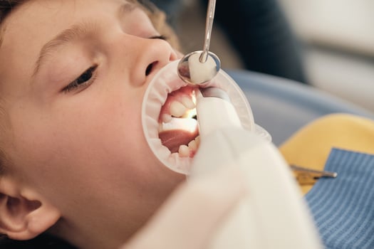 Faceless dentist scanning teeth of boy photo