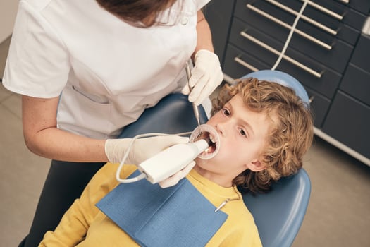 Crop dentist using intraoral scanner to preteen boy photo