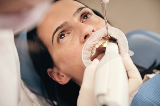 Crop dentist with 3D scanner serving female client photo