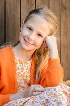 Smiling girl leaning on hand against wooden wall photo