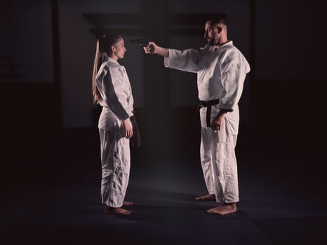 Man pointing gun to head of woman on training photo