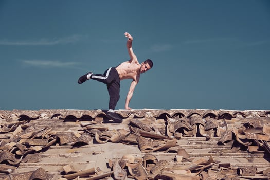 Athletic man performing handstand rotation while dancing breakdance on roof photo