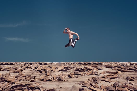 Strong active man jumping on roof while performing freestyle dance photo