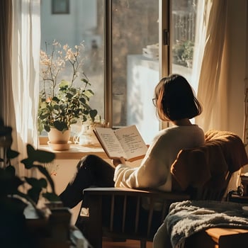 Young faceless woman reading a book in the living room, sitting by the window at home. Slow living concept. Menthal health concept. photo