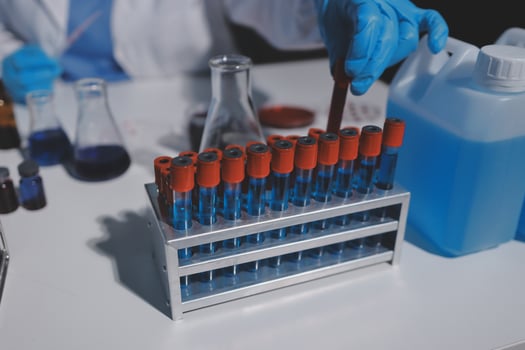 A person in a lab coat is holding a test tube photo