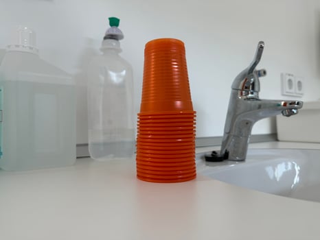 Stack of Orange Dental Plastic Cups on Countertop photo