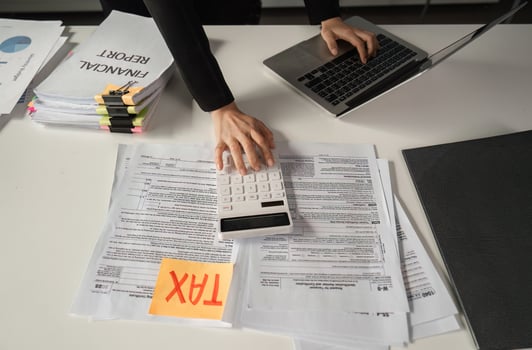 Businesswoman calculating finances using a calculator and managing tax paperwork. photo