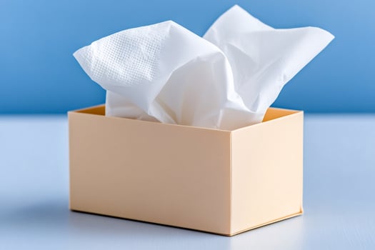White tissues emerging from beige dispenser on blue background photo
