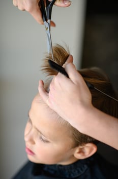 The child watches as his bangs are neatly trimmed by a stylist. photo