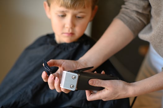 The hairdresser gently introduces the boy to the clipper, helping him feel more comfortable. photo