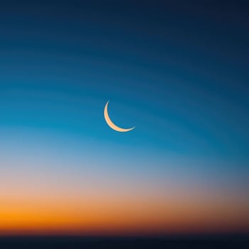 The crescent moon is seen in the sky at sunset photo