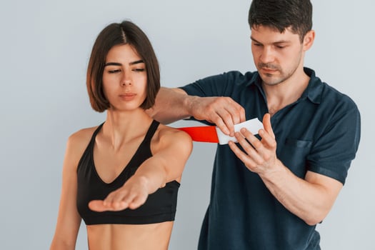 Focused worker. Woman visiting physiologist that putting kinesio tape on the skin, photo