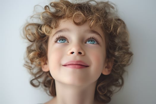 A cheerful Caucasian boy with curly hair gazing upwards with bright blue eyes, exuding innocence and joy. photo