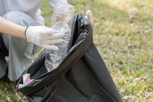 Individual collecting plastic bottles for recycling during a cleanup event in a park photo