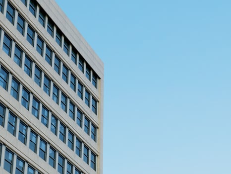Modern building corner with glass windows and a clear blue sky background. photo