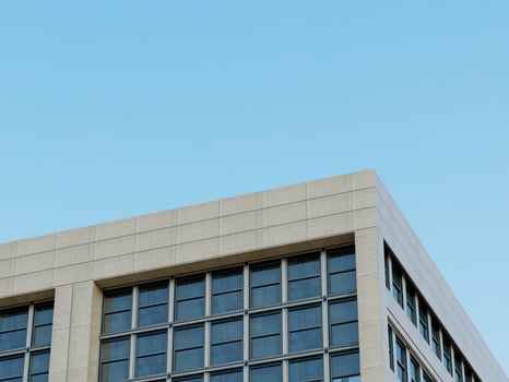 Contemporary office building corner with large glass windows against a blue sky. photo