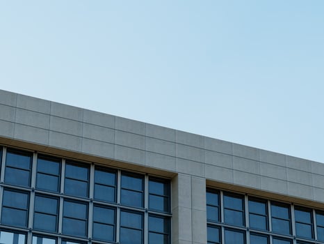 Modern high-rise building corner with a clear glass facade and blue sky. photo