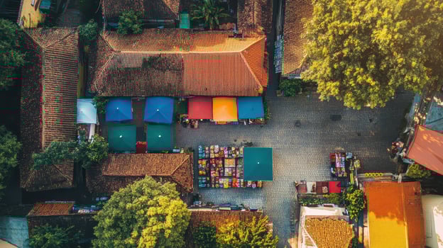 Aerial view of a vibrant market square with colorful tents and surrounding buildings. photo
