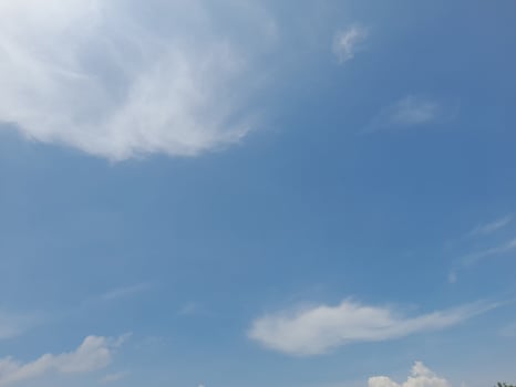 A bright blue sky with soft, wispy white clouds scattered across, creating a serene and peaceful atmosphere. photo