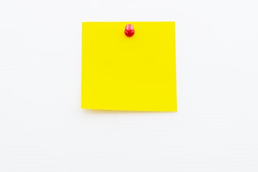 Bright yellow post note paper pinned on a white wall for reminders or messages photo