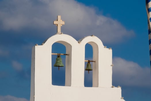 Two bells on top of a white church photo