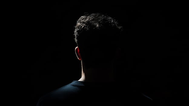 Silhouette of young caucasian male in darkness with curly hair photo