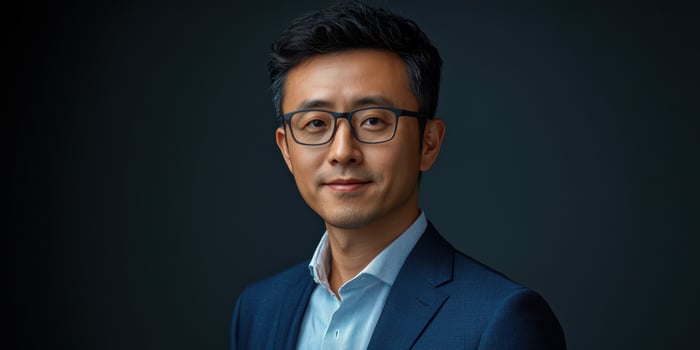Professional man poses in a dark setting wearing a suit and glasses during a relaxed portrait session photo