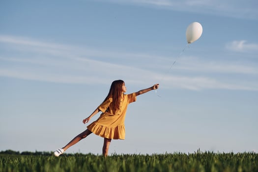 Playing with balloon. Happy girl have a walk outdoors on the field at summer., photo