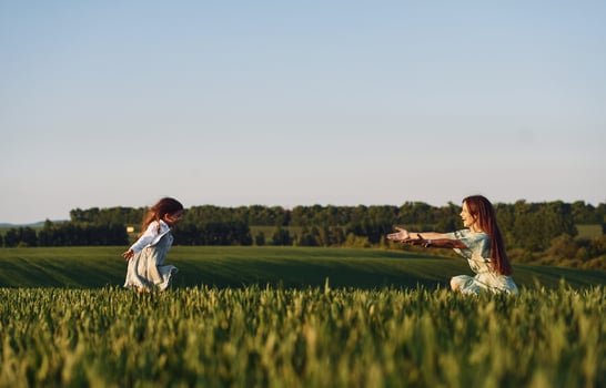 Little girl is running to the woman. Mother and daughter have fun outdoors on the field at summer. photo