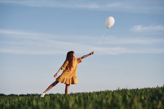 Playing with balloon. Happy girl have a walk outdoors on the field at summer. photo
