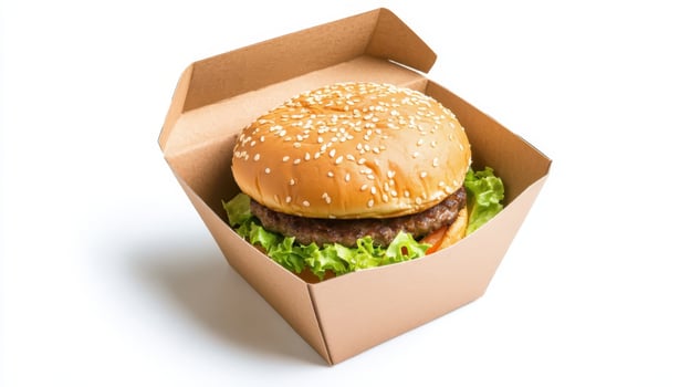 Freshly prepared hamburger with lettuce and sesame bun in a takeout box ready for a delicious meal at lunchtime photo