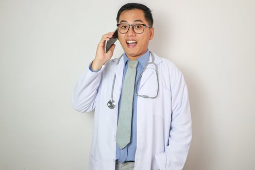 Telemedicine concept - asian male doctor talking to patient on smart phone online and looking the record by computer photo