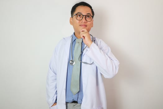 Studio shot of young multi-ethnic Asian man doctor wearing eyeglasses against white background photo