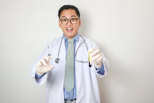 Portrait of a handsome Asian male doctor in uniform with a stethoscope. He was holding a syringe on an isolated background. photo