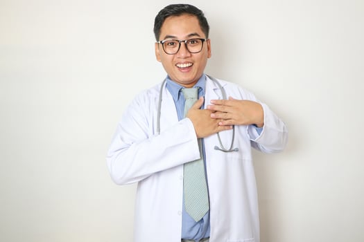A young Asian man wearing a white coat puts his hand on his chest in front photo