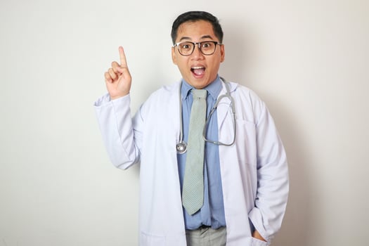 smart Asian doctor pointing finger on white background, he feeling happy and smiling photo
