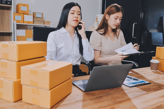 Two women in an office with boxes and papers photo