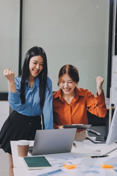Two women in business attire are celebrating photo