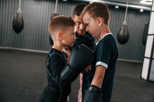 Pre fight preparing.. Looking at each other. Young tattooed coach teaching the kids boxing techniques photo