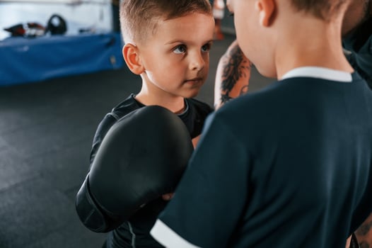 Pre fight preparing. Looking at each other. Young tattooed coach teaching the kids boxing techniques photo