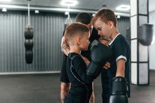 Preparing for the sparring. Young tattooed coach teaching the kids boxing techniques,. photo